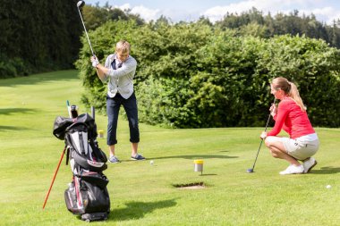Erkek golfçü yeşil golf golf topu koyarak