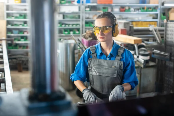 Trabalhadora operando uma máquina-ferramenta em oficina de metal ou fábrica — Fotografia de Stock