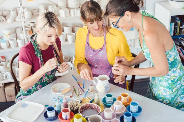 Учитель показывает женщинам в мастерской, как красить блюда, приготовленные самостоятельно — стоковое фото