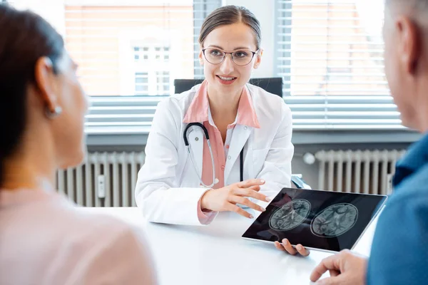 Médica mulher mostrando pacientes imagens de raios-x em seu computador tablet — Fotografia de Stock