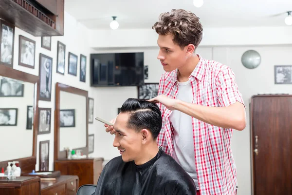 Stylist man looking in mirror sitting in the salon — Stock Photo, Image