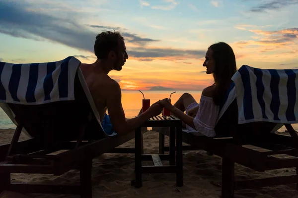 Para picie koktajli na plaży o zachodzie słońca podczas wakacji lub miesiąc miodowy — Zdjęcie stockowe