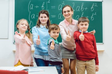 Okul sınıf odasında ki öğrenciler ve öğretmen başparmak-up gösteren