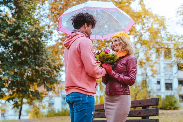 Homme noir donnant des fleurs à sa petite amie caucasienne en automne — Photo