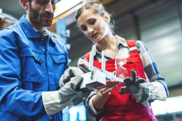 Trabajador de la mujer y del hombre que comprueba medidas de pieza de metal — Foto de Stock