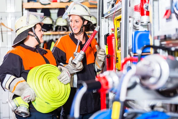 Fire fighters loading hoses into operations vehicle — Stock Photo, Image