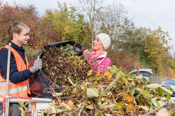 Frau und Mann geben Grünabfall im Container auf Recyclinghof ab — Stockfoto