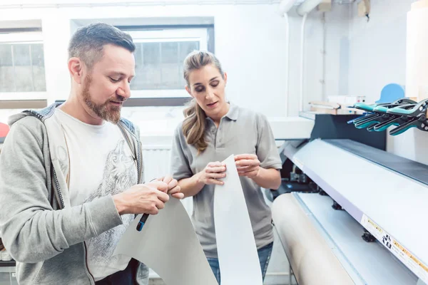 Man och kvinna som diskuterar en storformat print — Stockfoto