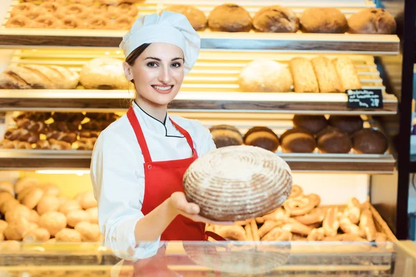 Verkäuferin mit Schürze präsentiert frisches Brot im Bäckerladen — Stockfoto
