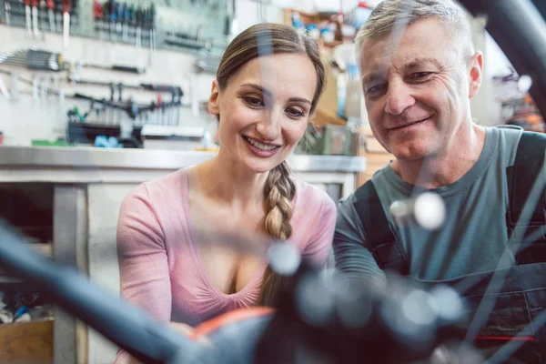 Fiets monteur en klant kijken naar de fiets die service nodig heeft — Stockfoto