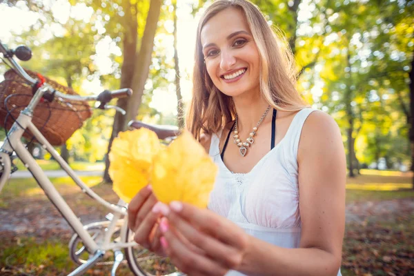 Frau stoppt ihr Fahrrad, um schönes Herbstlaub zu sammeln — Stockfoto