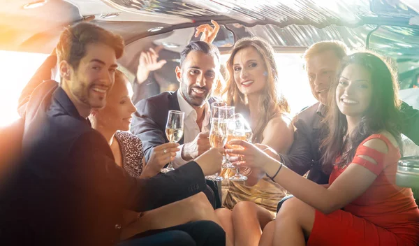 Group of women and men clinking glasses in a limousine — Stock Photo, Image