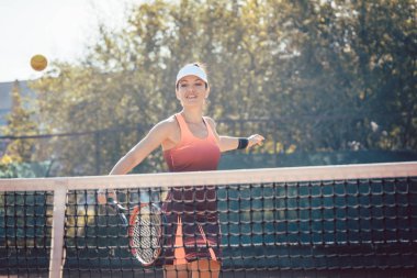 Kırmızı spor elbiseli kadın tenis oynuyor.