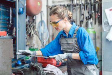 Metal atölyesinde kadın işçi iş parçası deburring