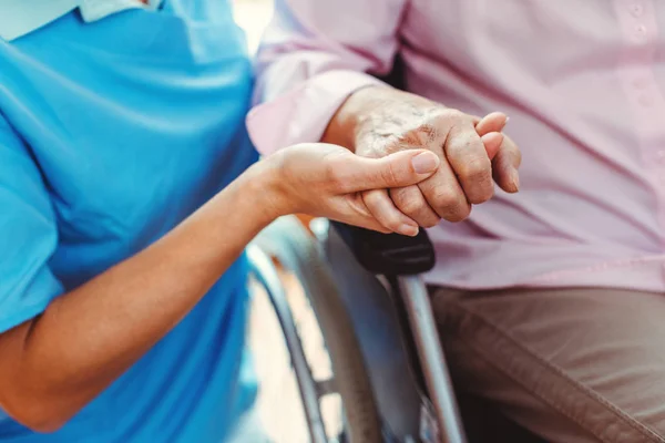 Enfermera consolando a una mujer mayor en el asilo sosteniendo su mano — Foto de Stock