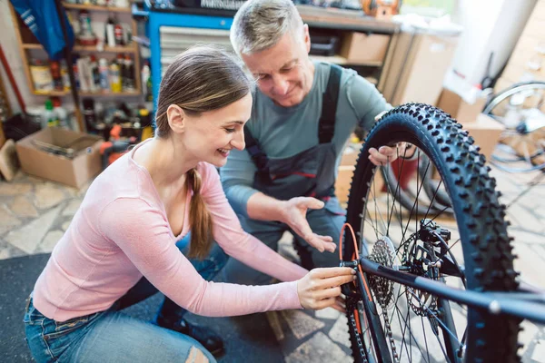 Bike μηχανικός και πελάτης κοιτάζοντας το ποδήλατο που χρειάζεται σέρβις — Φωτογραφία Αρχείου