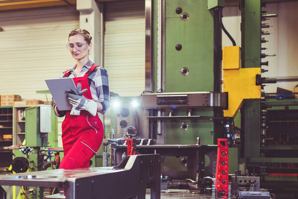 Woman worker with tablet computer in front of machine