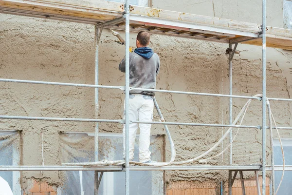 Werknemer bepleistering buitenste muur van nieuw gebouwde huis — Stockfoto