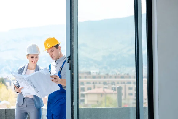Opdrachtgever en bouwer lezen blauwdrukken op bouwplaats — Stockfoto