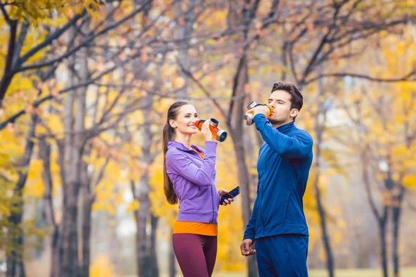 Deporte pareja beber agua teniendo descanso de correr — Foto de Stock