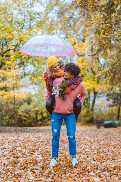 Preto homem carregando seu caucasiano menina piggyback no outono — Fotografia de Stock