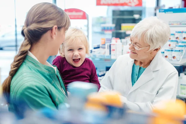 Vänlig farmaceut, mor och barn ha kul i farmaci — Stockfoto