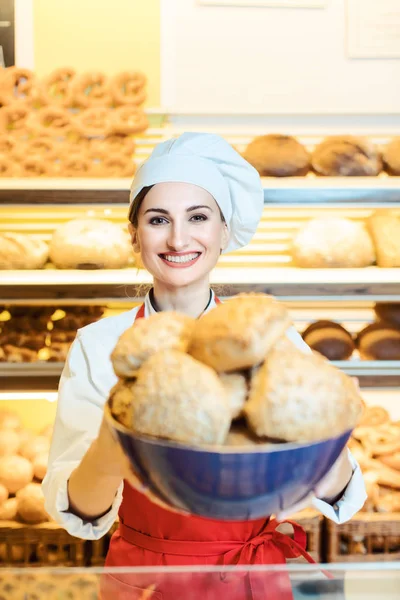 Φρέσκο ψωμί που παρουσιάζεται από μια ελκυστική νεαρή πωλήτρια στον φούρνο — Φωτογραφία Αρχείου