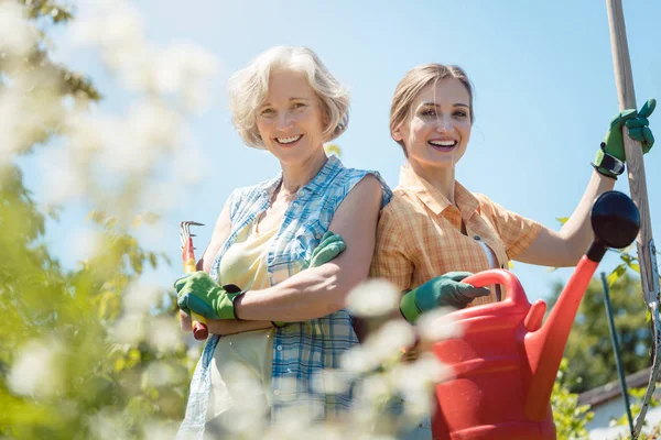 Ung och senior kvinna poserar för fotot i deras trädgård — Stockfoto
