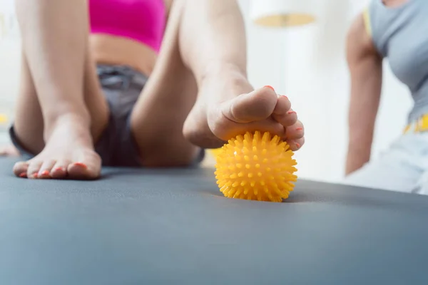 Mujer rodando bola de púas bajo sus pies en la terapia física —  Fotos de Stock