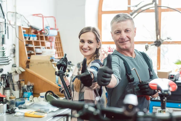 Deux mécaniciens de vélo dans leur atelier ayant une journée réussie — Photo
