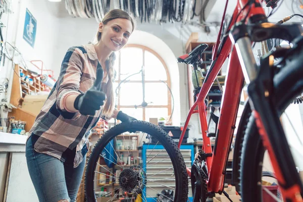 Femme mécanicien de vélo dans son atelier changer un pneu — Photo