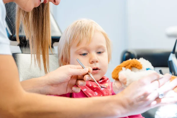 Dentista explicando o tratamento para uma criança usando um brinquedo de pelúcia — Fotografia de Stock