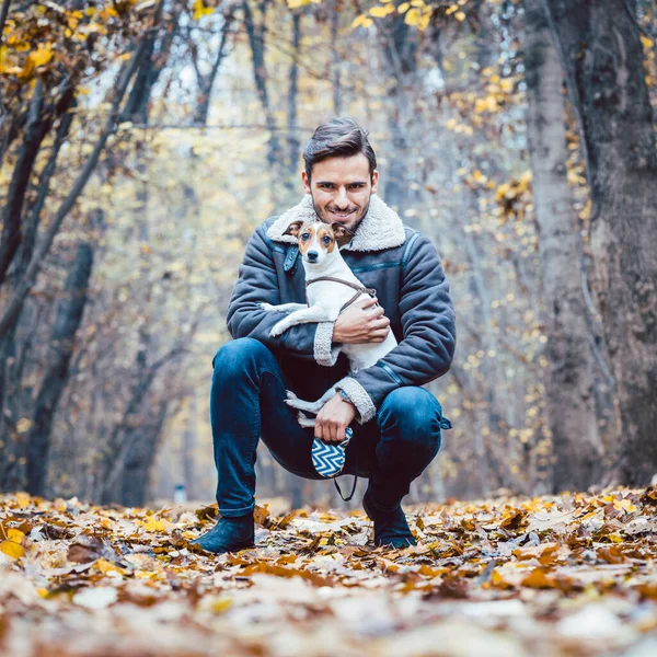 Jeune homme promenant son chien faisant une promenade dans le parc d'automne — Photo