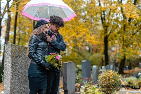 Couple in grief on a cemetery in fall — Stock Photo, Image