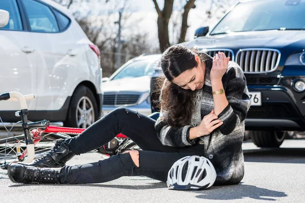 Femme blessée assise par terre après un accident de vélo — Photo