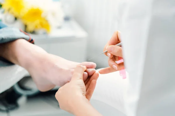 Podólogo cortando las uñas en los pies del hombre durante la pedicura — Foto de Stock