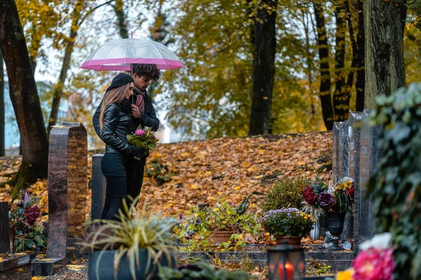 Man och kvinna på en kyrkogård med blommor — Stockfoto