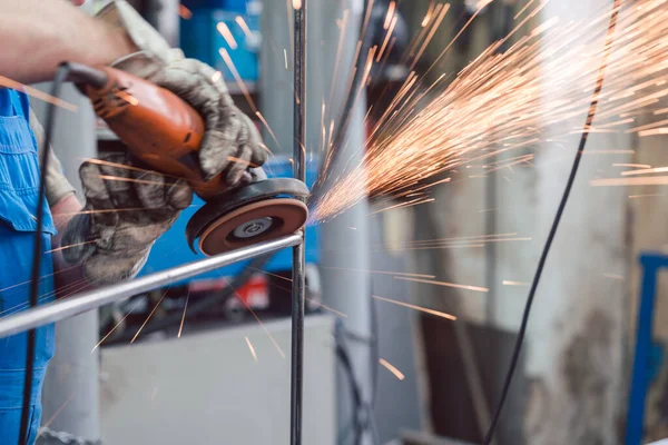 Worker in metal factory grinding workpiece with sparks flying — Stock Photo, Image