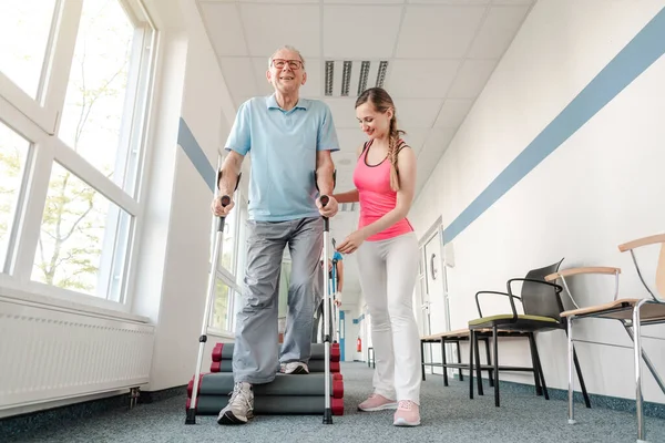 Пенсионеры в реабилитации учатся ходить с костылями — стоковое фото