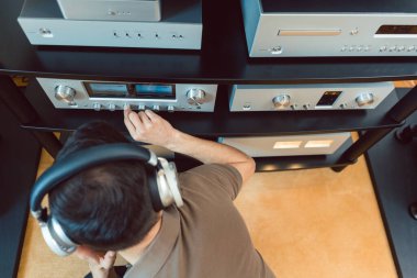 Man turning up the volume on home Hi-Fi stereo clipart