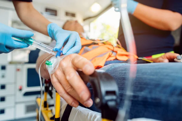 Emergency doctor administering injection needle in ambulance — Stock Photo, Image