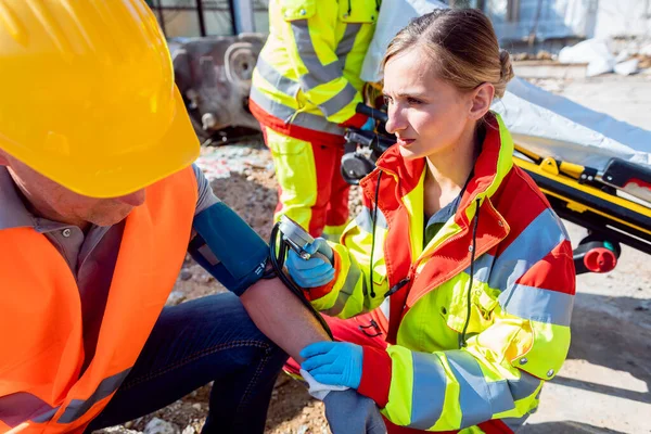Paramedisk mätning av blodtryck och samtal med människa efter olycka — Stockfoto