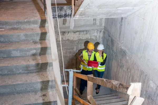 Ouvrier de la construction et constructeur inspectant les escaliers dans la coque du bâtiment — Photo