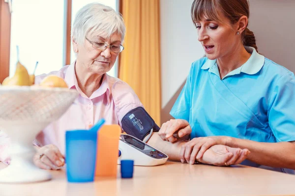 Nurse measuring blood pressure on senior woman — Stock Photo, Image