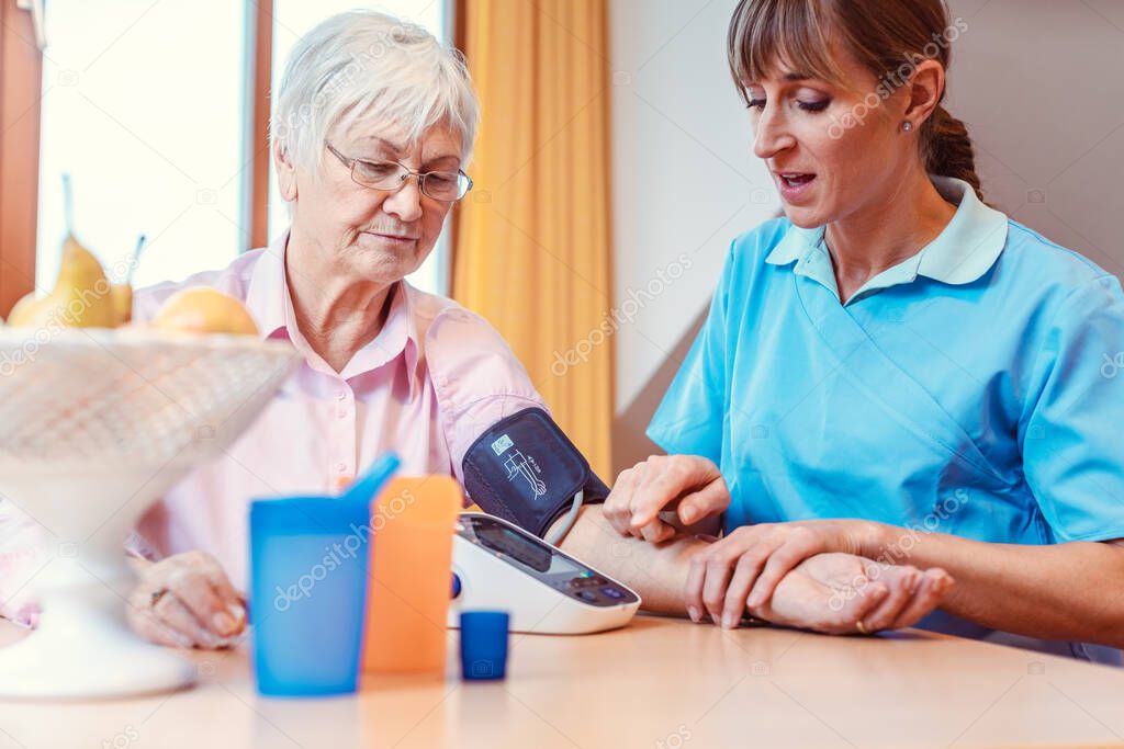 Nurse measuring blood pressure on senior woman