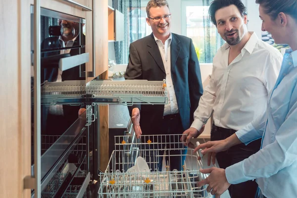 Couple checking dishwasher of new kitchen in the showroom — Stock Photo, Image