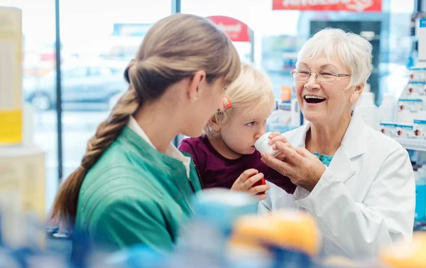 Farmacista amichevole, madre e bambino si divertono in farmacia — Foto Stock
