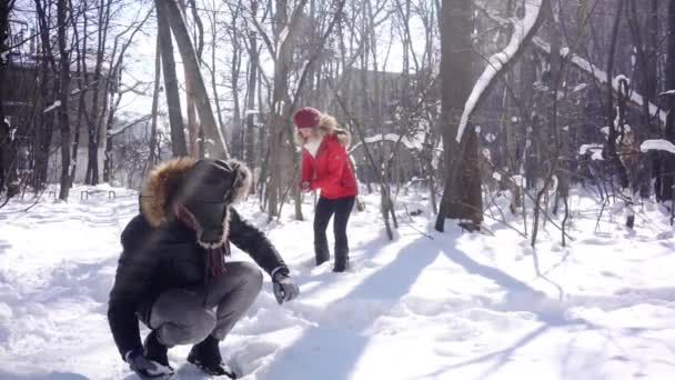 Donna che lancia palla di neve sul suo ragazzo in inverno di umore giocoso — Video Stock