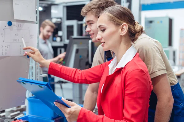 Werknemer en manager op fabrieksvloer bespreken productspecificaties — Stockfoto