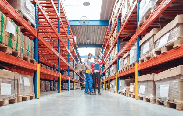Werknemersteam staat tussen hoge stellingen in logistiek magazijn — Stockfoto